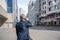 Alone middle-aged gray-haired businessman in a blue suit calling by phone standing on the empty city street.