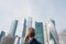 Alone middle-aged gray-haired businessman in a blue suit calling by phone standing opposite Moscow City skyscrapers.Low angle view