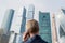 Alone middle-aged gray-haired businessman in a blue suit calling by phone standing opposite Moscow City skyscrapers.Low angle view