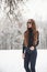Alone in the park. Pretty girl with long hair in black blouse and eyewear is in the winter forest