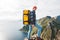 Alone professional traveler with backpack on high mountain standing on the edge cliff rock and looking away