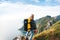 Alone professional traveler with backpack on high mountain standing on the edge cliff rock and looking away