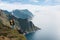 Alone professional traveler with backpack on high mountain standing on the edge cliff rock and looking away