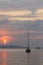 Alone sailboat at sunset. Atmospheric seascape with orange sun.