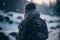 Alone soldier, standing with a backpack, against the backdrop of a winter landscape