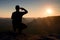 Alone sportsman in black. Tall hiker in squatting position enjoy view at sunset on mountain peak