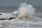 Alone surfer in wetsuits with surfboard on a city pier amid powerful waves in Australia. Concept: confrontation between the