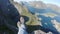 Alone traveler sitting on a mountain edge above a Reine city, Lofoten, Norway.