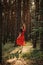 Alone Woman in red dress dance on sun pine forest nature background