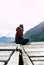 Alone women relax on wooden dock at peaceful lake. Girl meditation with red jacket in a wood pier