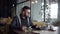 Alone young man is resting alone in cafe in daytime, using tablet and sipping hot drink tea from cup