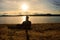 Alone Young Man In Silhouette Sitting In The Sun On Beach. Tourist take rest on wooden bench at autumn lake.