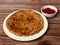 Aloo Paratha or Indian Potato stuffed Flatbread. Served with tomato ketchup. isolated over a rustic wooden background, selective