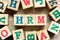 Alphabet block in word  HRM Abbreviation of human resource management with another on wood background