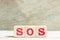 Alphabet block in word SOS abbreviation of save our soul/ship or sibling over shoulder on wood background