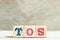 Alphabet block in word TOS abbreviation of Terms of service on wood background