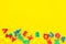 Alphabet for kids concept. English letters in disorder on yellow background top view copy space