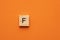 Alphabet letter F on wooden square tile - Orange foamy background