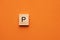 Alphabet letter P on wooden square tile - Orange foamy background