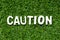 Alphabet letter in word caution on green grass background