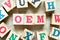 Alphabet letter in word OEM Abbreviation of Original Equipment Manufacturer with another on wood background