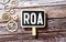 Alphabet letter in word ROA Abbbreviation of Return on assets on wood background