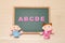 Alphabet letters ABCDE and children dolls on blackboard. English education concept.