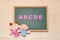 Alphabet letters ABCDE and children dolls on blackboard. English education concept.