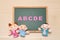 Alphabet letters ABCDE, children dolls and man doll on blackboard. English education concept.
