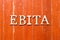 Alphabet in word EBITA abbreviation of  earnings before interest, taxes and amortization on old red color wood plate