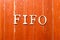 Alphabet in word FIFO Abbreviation of first in first out on old red color wood plate background