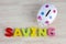 Alphabet word SAVING  and white piggy bank on wooden desk