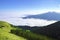 Alpin view to a valley above clouds. Apennines mountains in summer. Green grass and forest, mountain in background