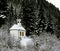 alpine chapel in a winter landscape with a forest background