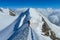 Alpine climber on sharp knife-edged snow mountain ridge