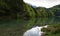 alpine lake Alatsee, the snowy Bavarian Alps and spring forest reflected in the water , Bavaria, Germany