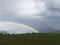 Alpine landscape with beautiful rainbow. Mountains, meadows and pastures with sunbow.