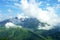 Alpine meadows, mountains and lots of white clouds with beautiful summer landscape