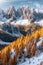 The alpine mountains of the Dolomites in autumn, with white rocks covered in light snow and orange larches