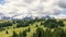 Alpine plateau with pine forests in the rays of the sun and the Dolomites covered with snow