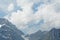 Alpine scenery with cables for cable car transport in the foreground. The sky is covered with thick white clouds and the rests of