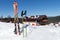 Alpine skiing with sticks stand in a white snowdrift against the background of the Swiss cottage