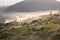 Alpine village in mountains. Smoke, bonfire and haze over hills