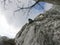 Alpinist with blue backpack and climbing gear climbing on the limestone rock.