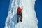 Alpinist man with ice tools axe climbing a large wall of ice. Outdoor Sports Portrait
