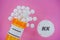 Alprazolam Rx medicine pills in plactic vial with tablets. Pills spilling from yellow container on pink background