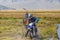 Altai, Mongolia - June 14, 2017: Mongolian nomad looks at tourists wich motorcycle stuck in mud