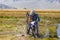 Altai, Mongolia - June 14, 2017: Mongolian nomad looks at tourists wich motorcycle stuck in mud