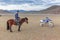 Altai, Mongolia - June 14, 2017: Mongolian rider stopped next to a motorcycle and looks at tourists