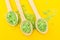 Alternative healthcare concept. Green Salt in three wooden spoons on a yellow background. Top view